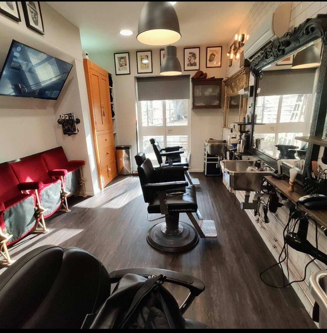 The row of barber chairs and basins beneath ornate black mirrors